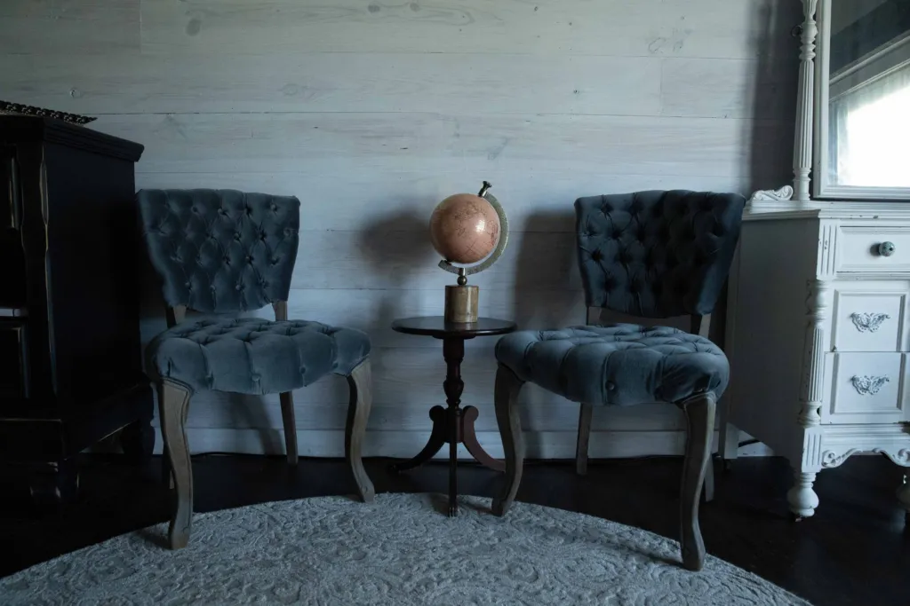 Two tufted chairs and a vintage globe in the bridal suite