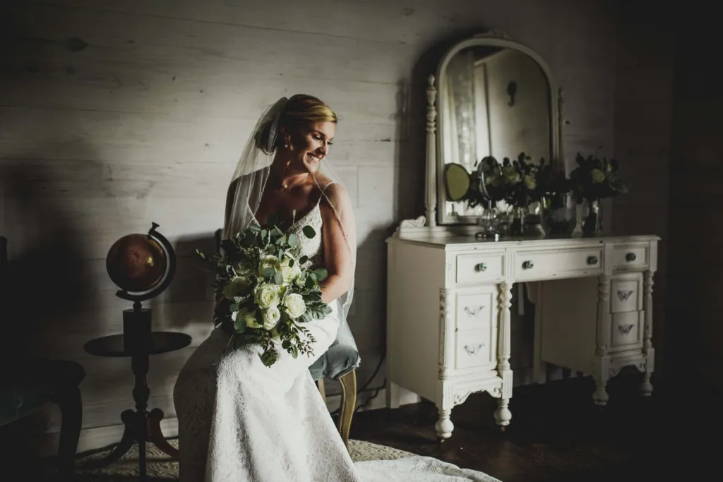 Bride seated at the vanity holding her bouquet