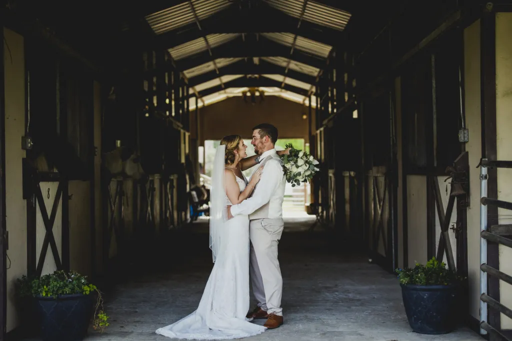 Couple embracing in the center aisle of the horse barn