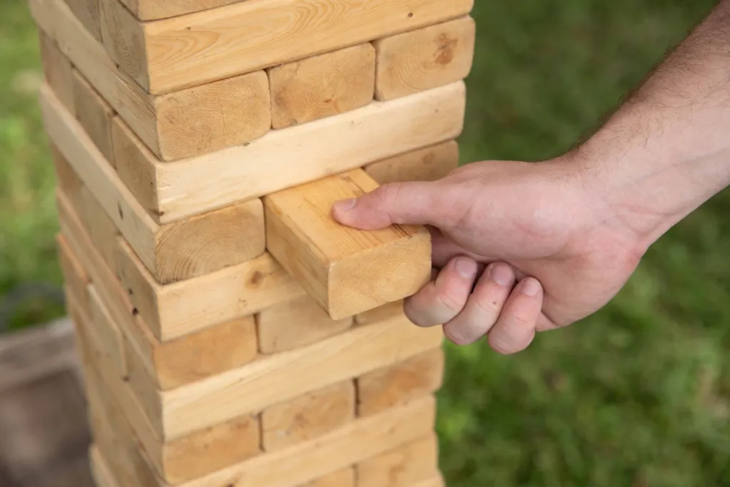 Guest pulling a block from a giant yard Jenga tower