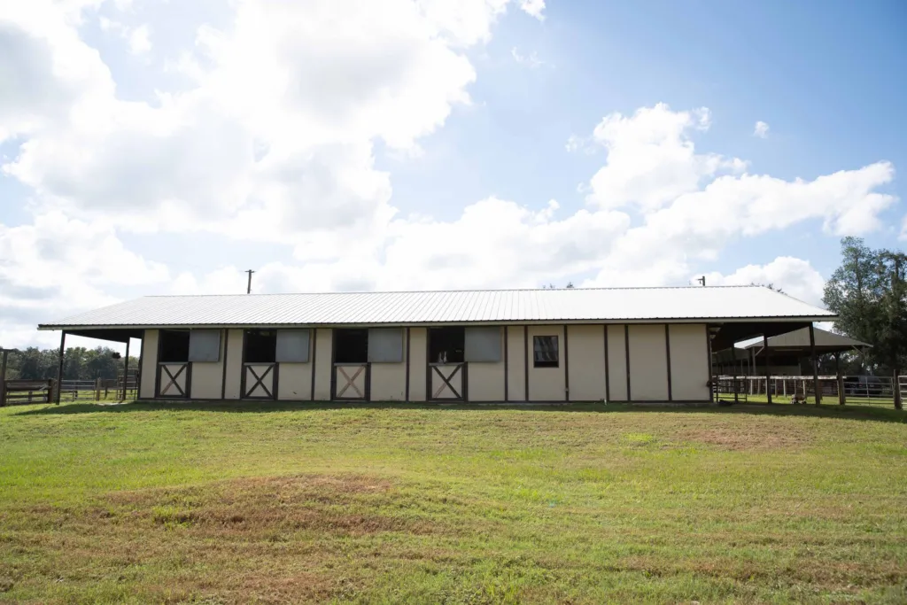 Long view of the horse barn across green pasture