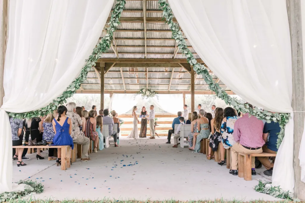 View down the aisle of a pavilion ceremony framed by white curtains