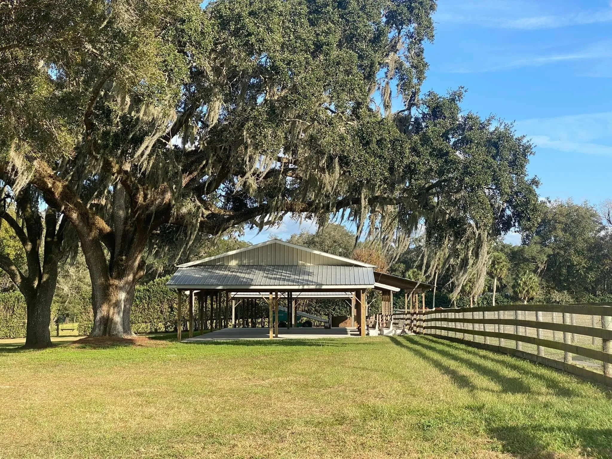 Open-air pavilion beside the pasture fence under moss-draped live oaks