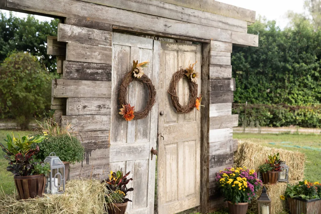 Rustic wooden doors with wreaths, hay bales and potted mums