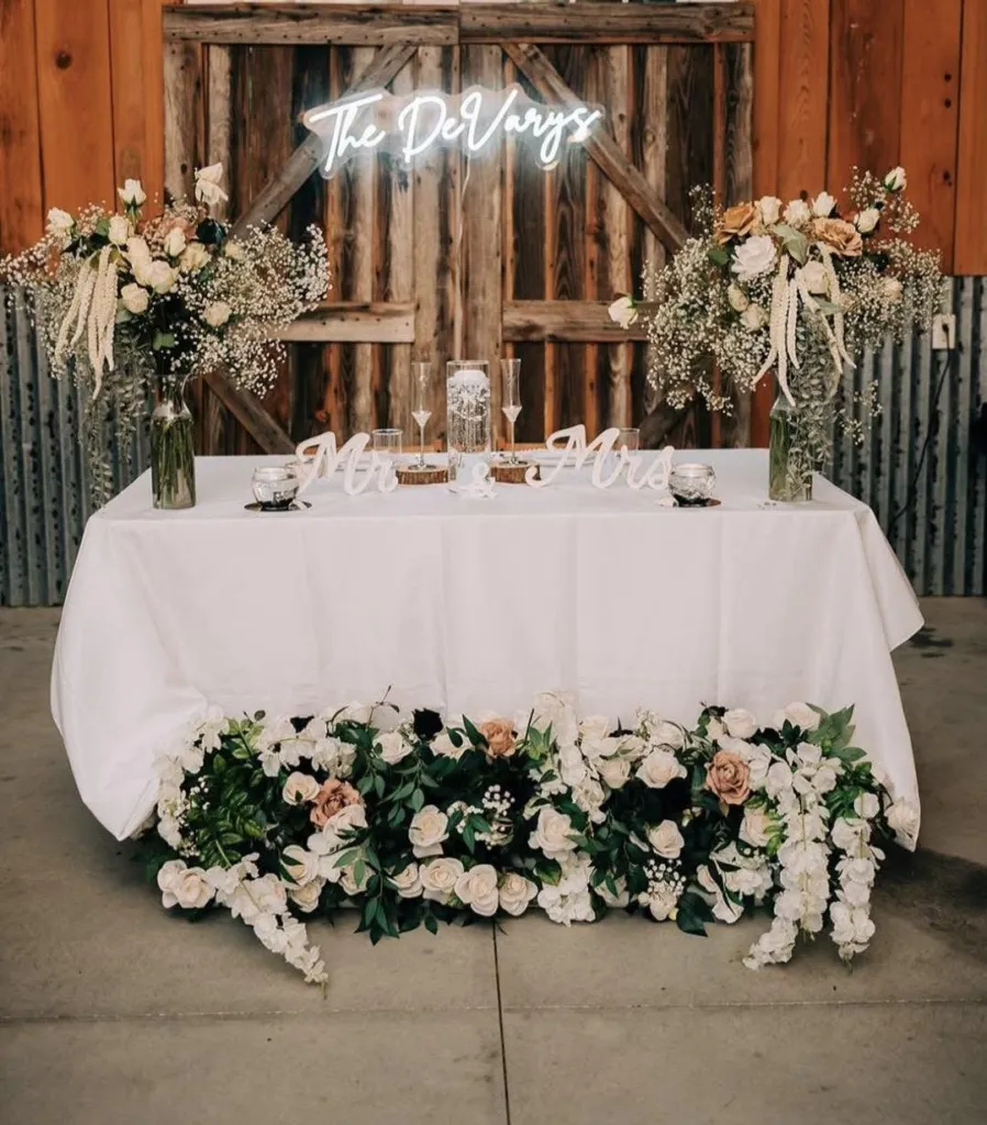 Sweetheart table dressed in white with a floral garland