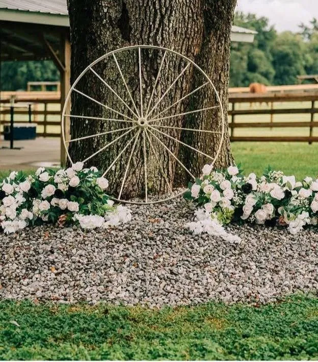 Wagon wheel framed with white flowers at the base of an oak